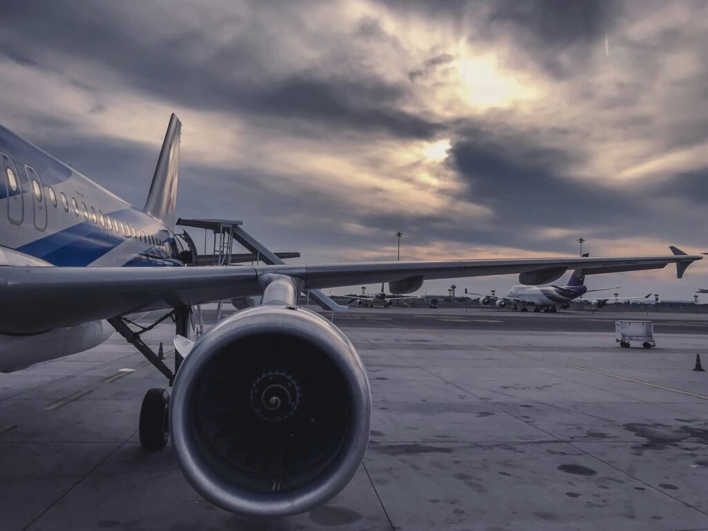 Coorg Car transfer A passenger airplane is parked on the tarmac at sunset, with another aircraft in the background.